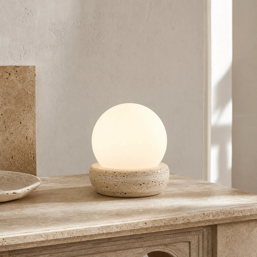 Mirelle modern travertine globe table lamp glowing on a stone console