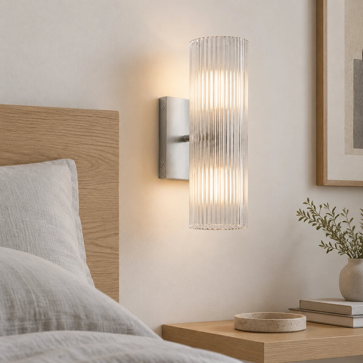 Nickel Cian wall light with ribbed glass beside an oak headboard